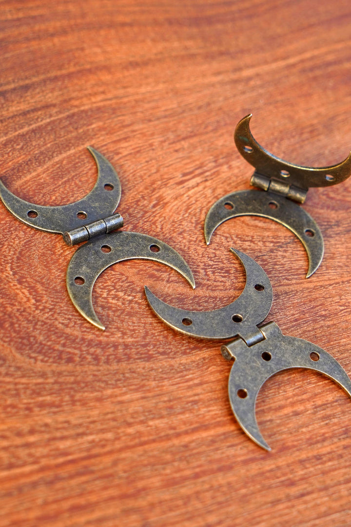Bronze and steel crescent moon hinges with screws, close-up on wood