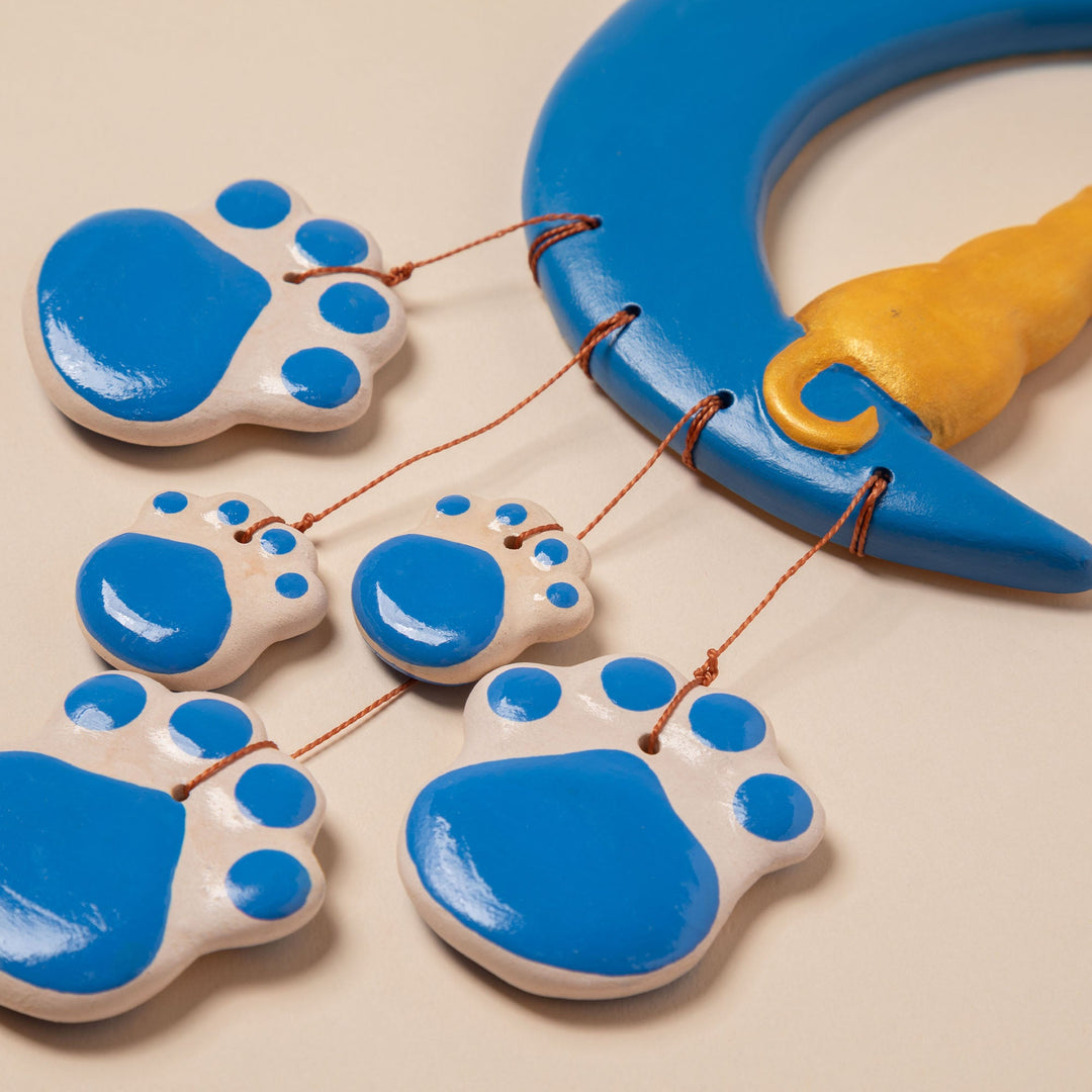 Close-up of ceramic blue paw discs with copper strings and curved moon piece