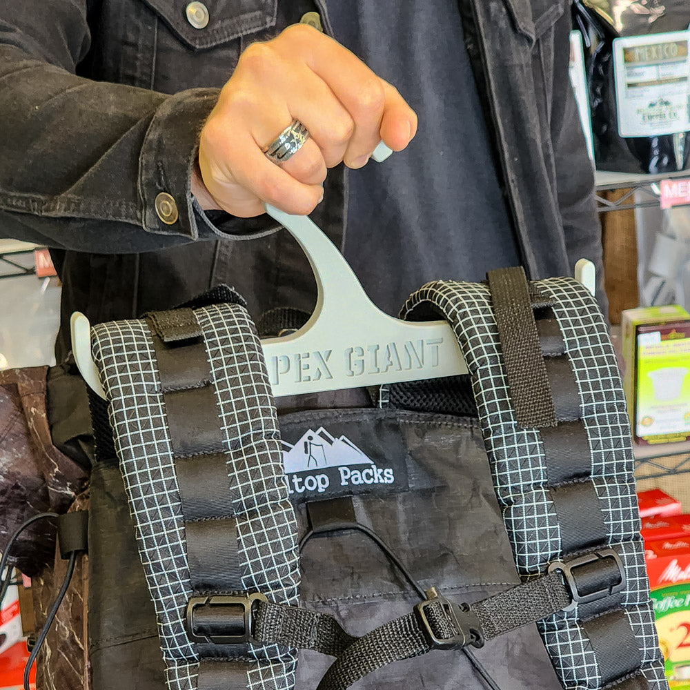 Gray backpack hanger holding a patterned backpack, curved hooks visible