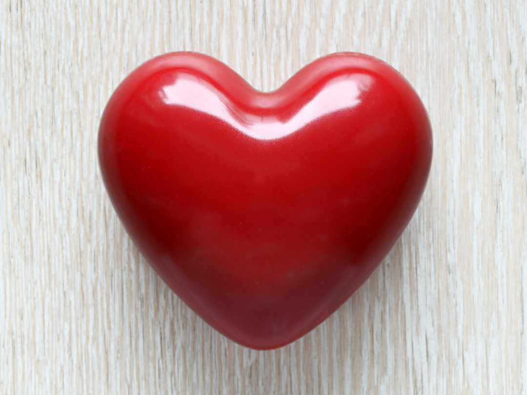 Glossy red heart wax freshener on a light woodgrain surface