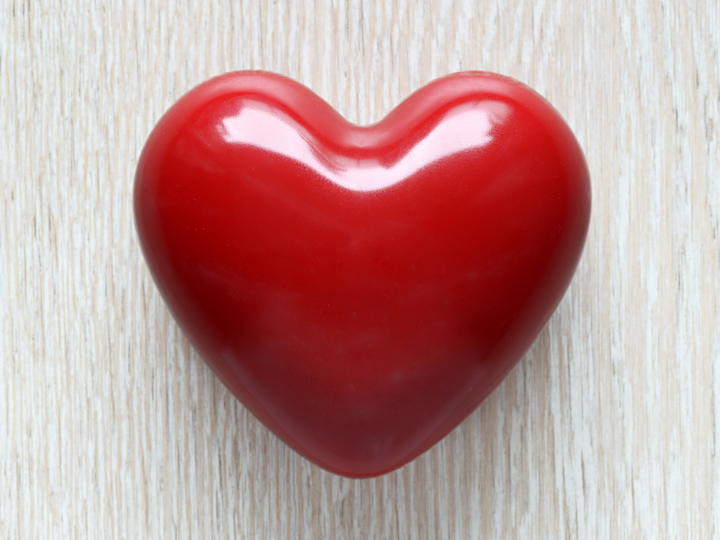 Glossy red heart wax freshener on a light woodgrain surface