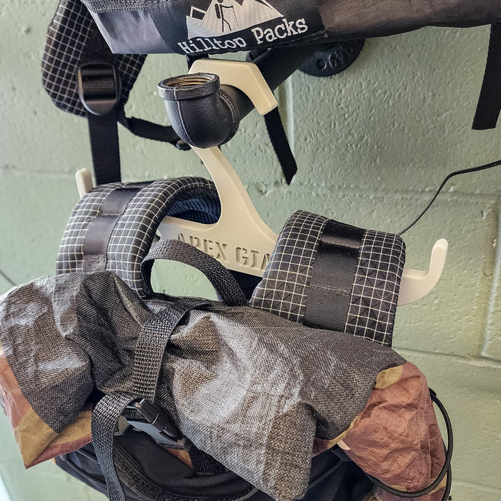 Light gray backpack hanger with curved hooks holding a backpack bag