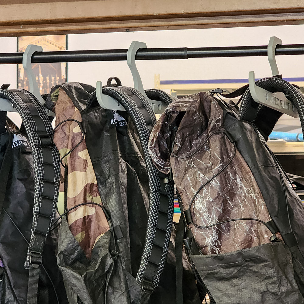 Plastic backpack hangers on a bar holding multiple backpacks