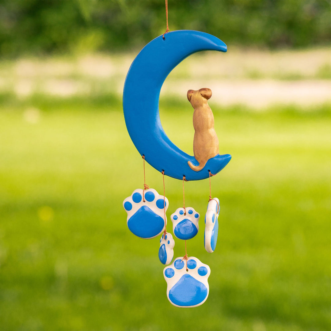 Outdoor view of blue ceramic moon wind chime with cat figure and dangling paw discs