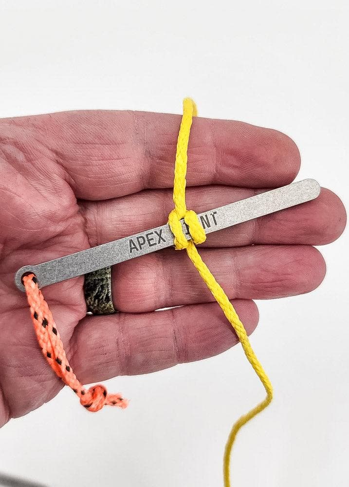 Bear bag toggle on hand with grey bar, orange cord and yellow line