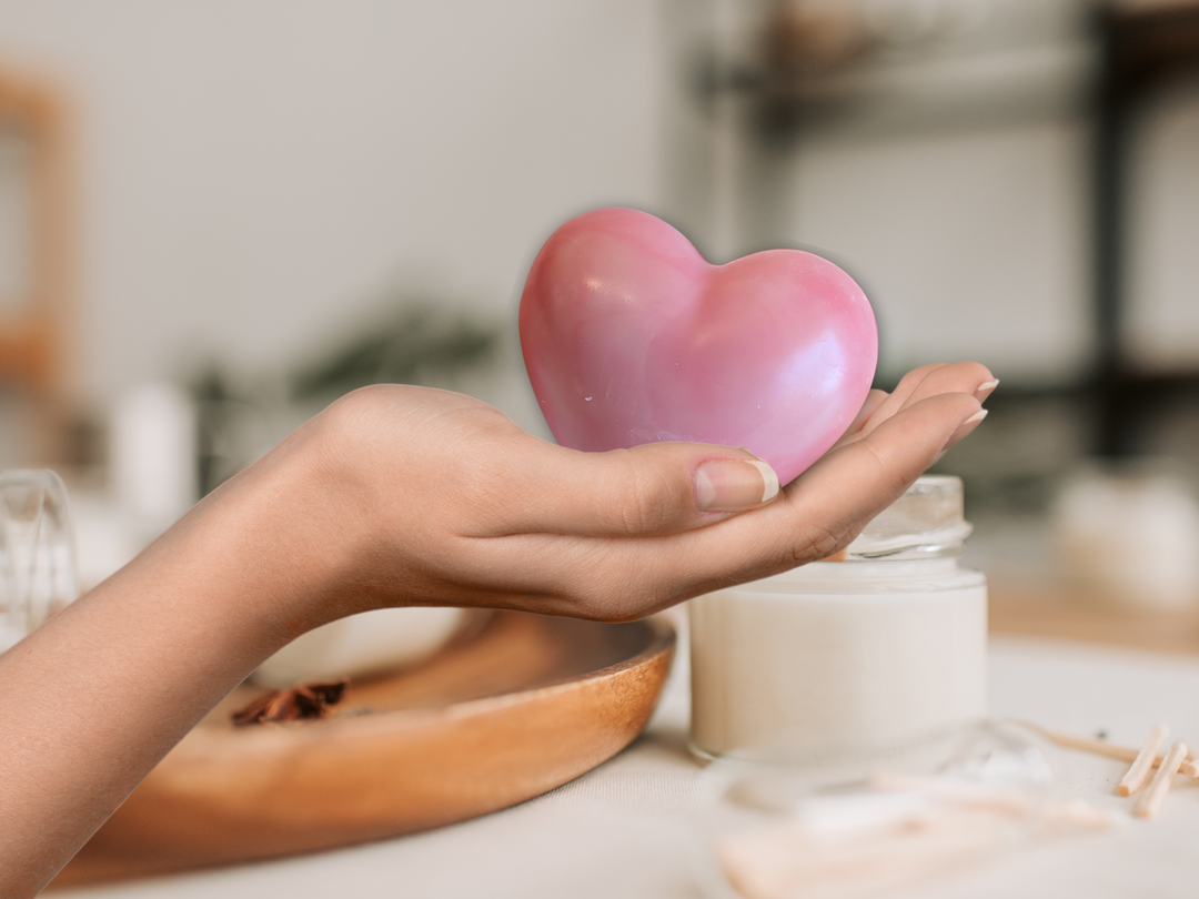 Pink heart wax freshener held in a hand above a candle-like container