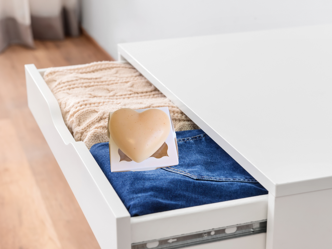 Cream heart wax freshener inside a drawer box over folded denim