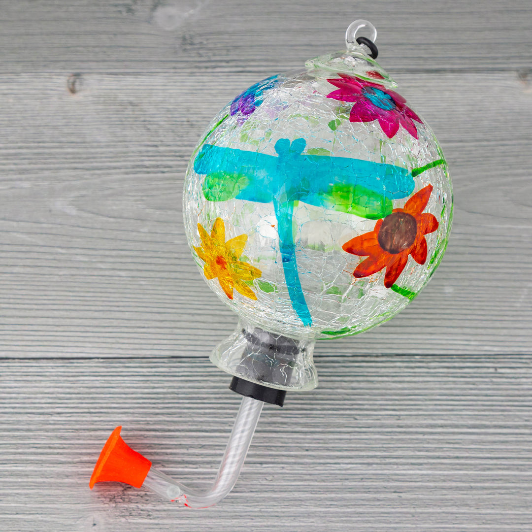Hanging glass hummingbird feeder with blue and green shapes, yellow flower, and orange butterfly