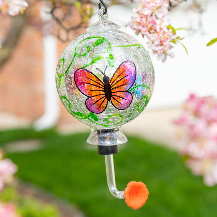 Hand-painted glass hummingbird feeder with green vines and a colorful butterfly design