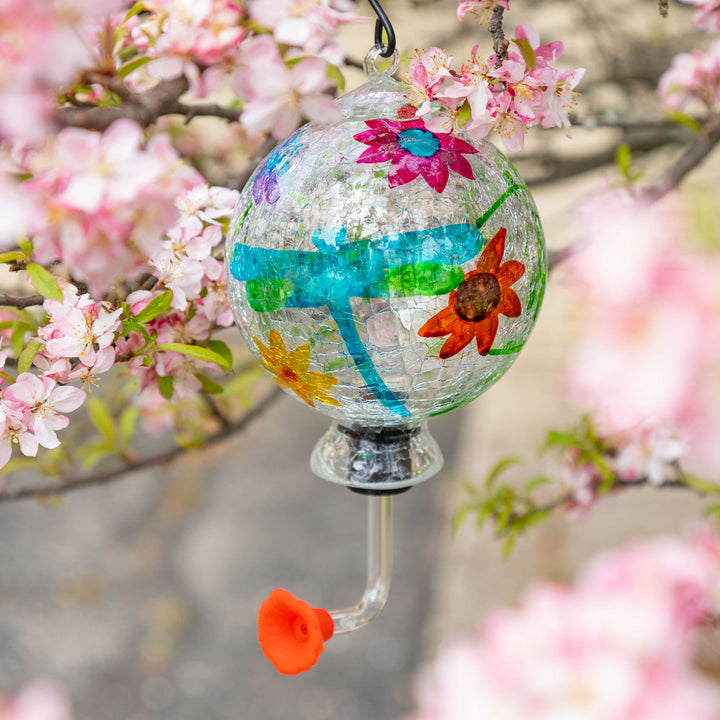Hand-painted glass hummingbird feeder with blue paneling, pink flower, and orange butterfly