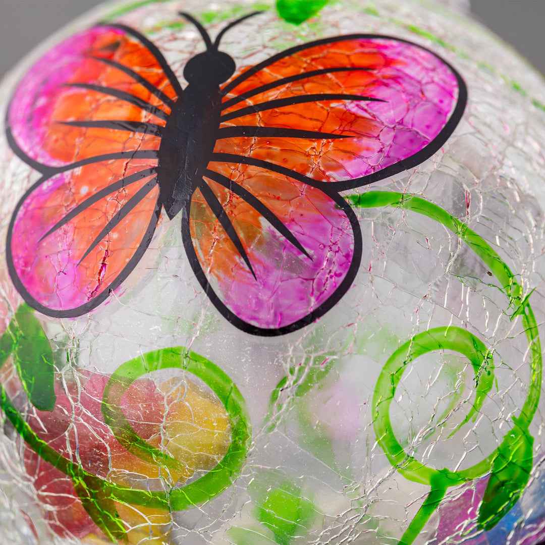 Close-up of hand-painted glass hummingbird feeder globe with a purple-orange butterfly