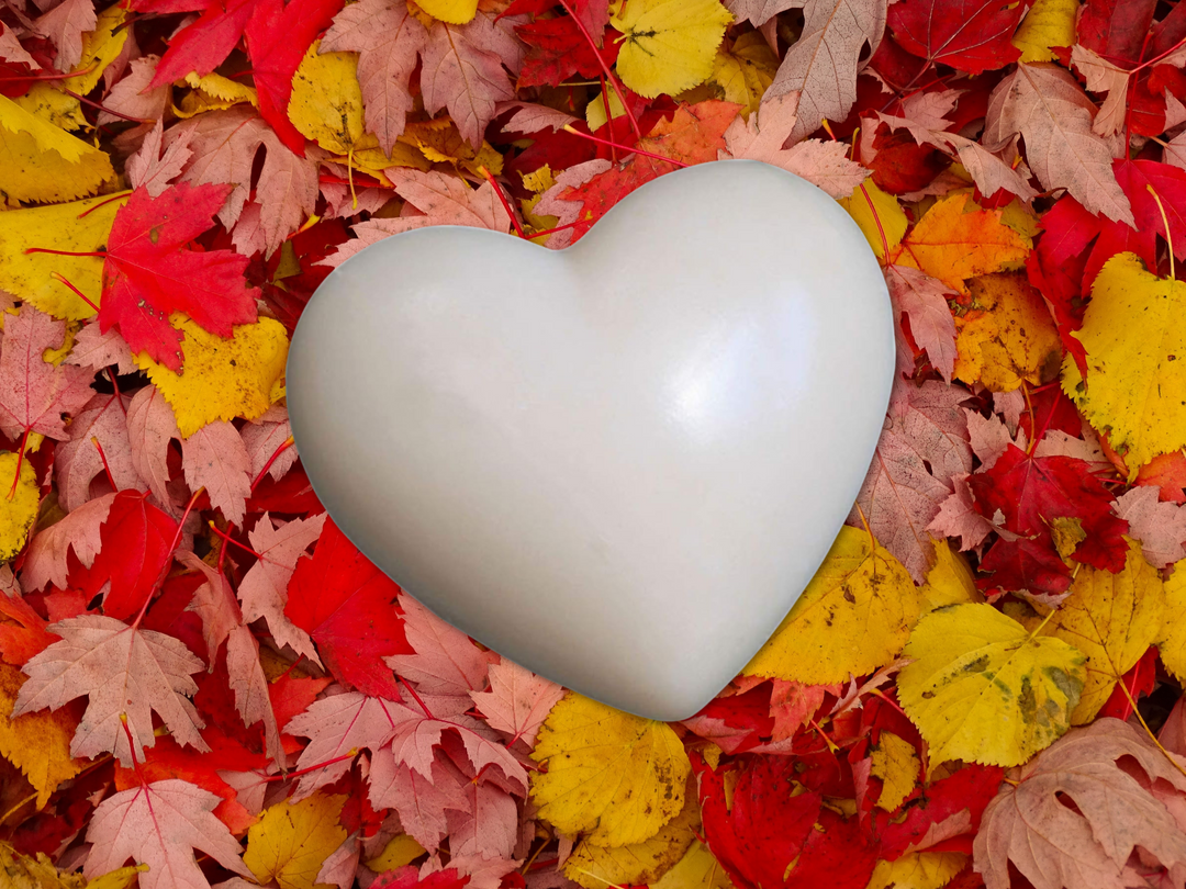 White heart-shaped wax sachet surrounded by fall leaves