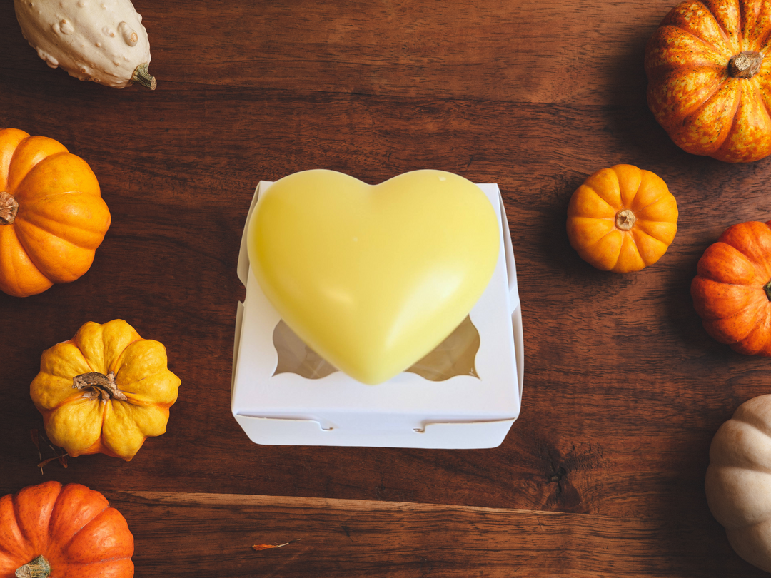 Yellow heart-shaped wax sachet in an open white box on a dark wooden table