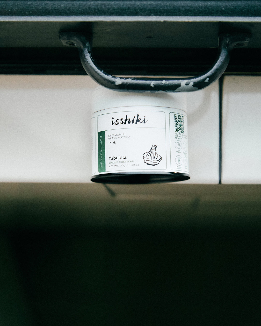 Small ceremonial matcha tin on a shelf ledge, label facing forward