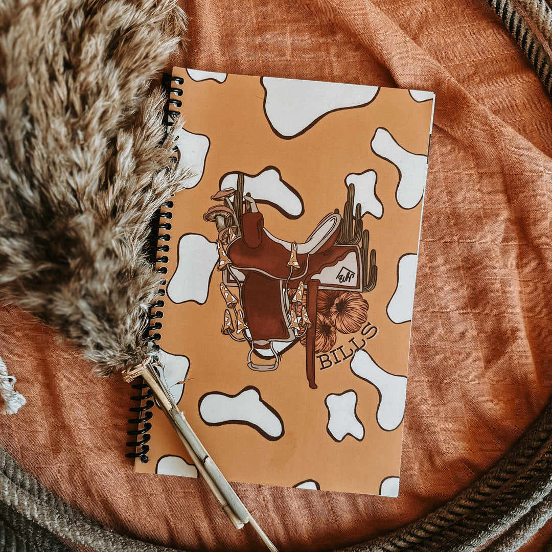 Spiral bill tracker notebook with western saddle and cow-print cover