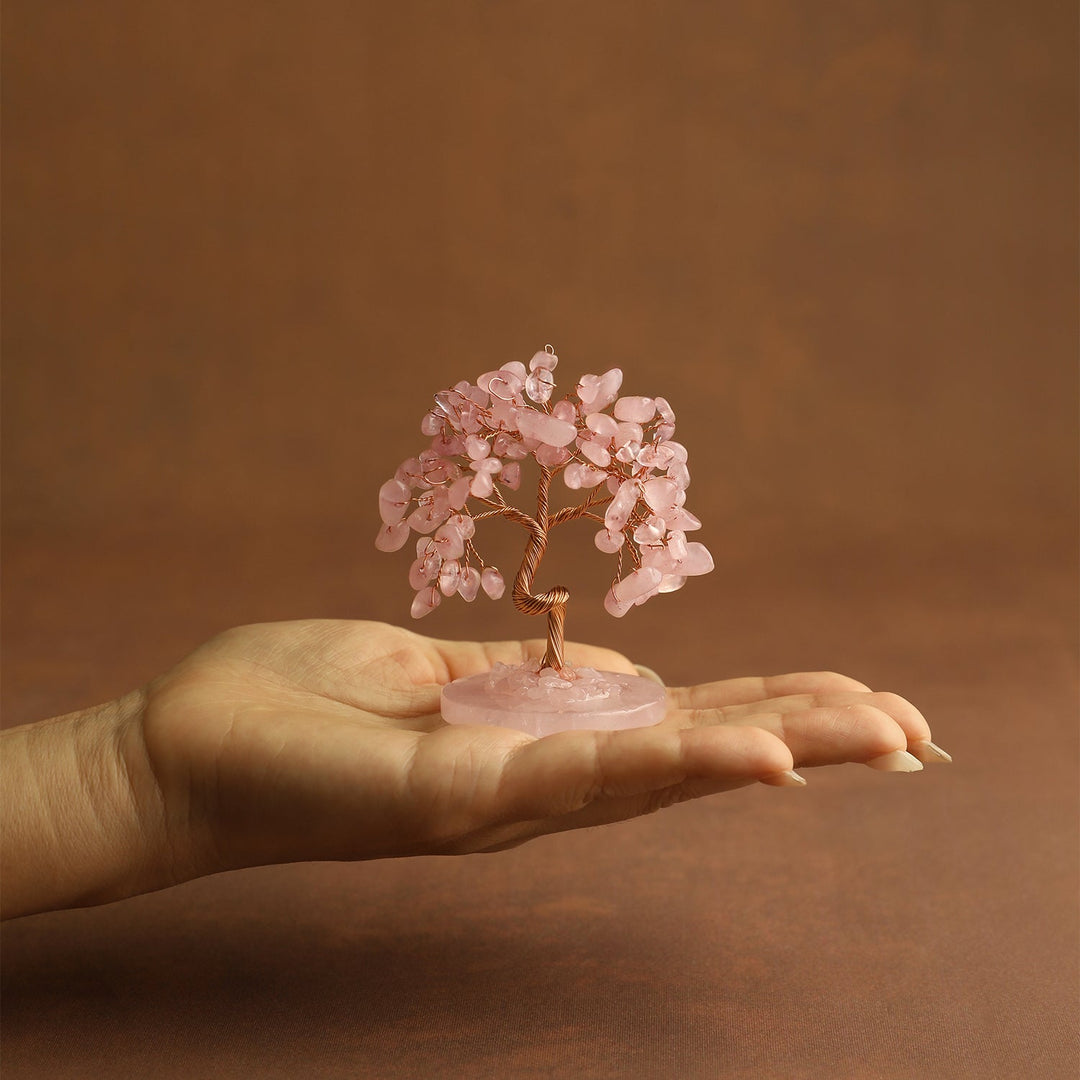 Pink crystal tree ornament held in a hand on a small pink round base