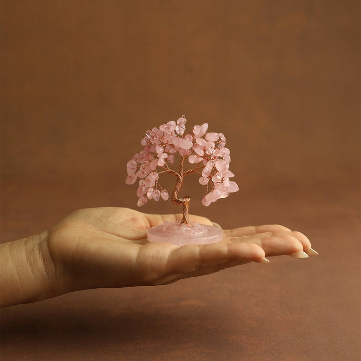Pink crystal tree ornament held in a hand on a small pink round base