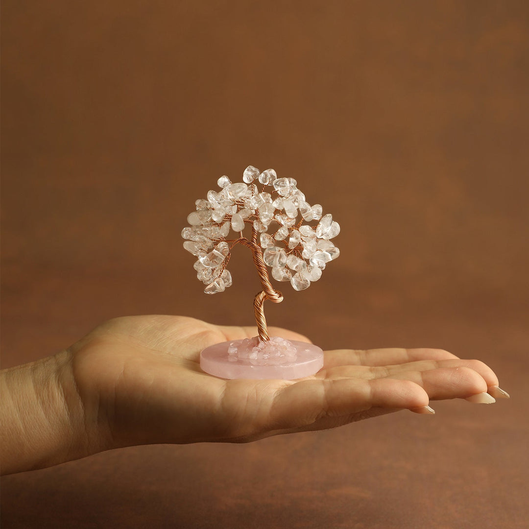 Clear crystal tree ornament held in a hand on a small pink round base