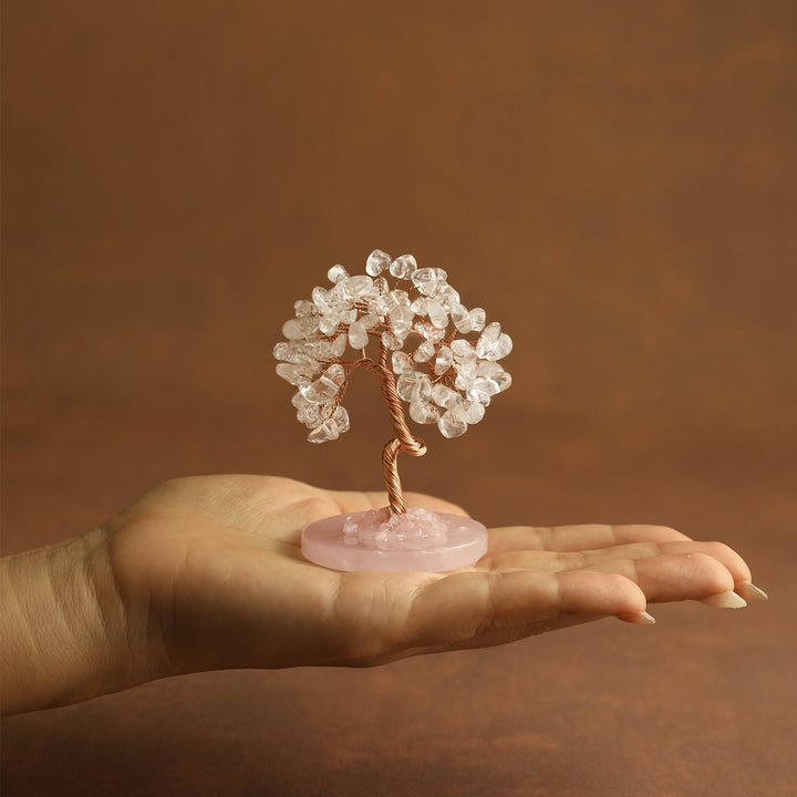 Clear crystal tree ornament held in a hand on a small pink round base