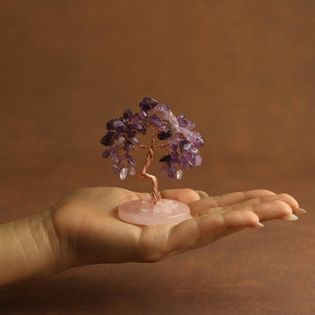 Purple gemstone mini crystal tree on pink stone base, held in open palm