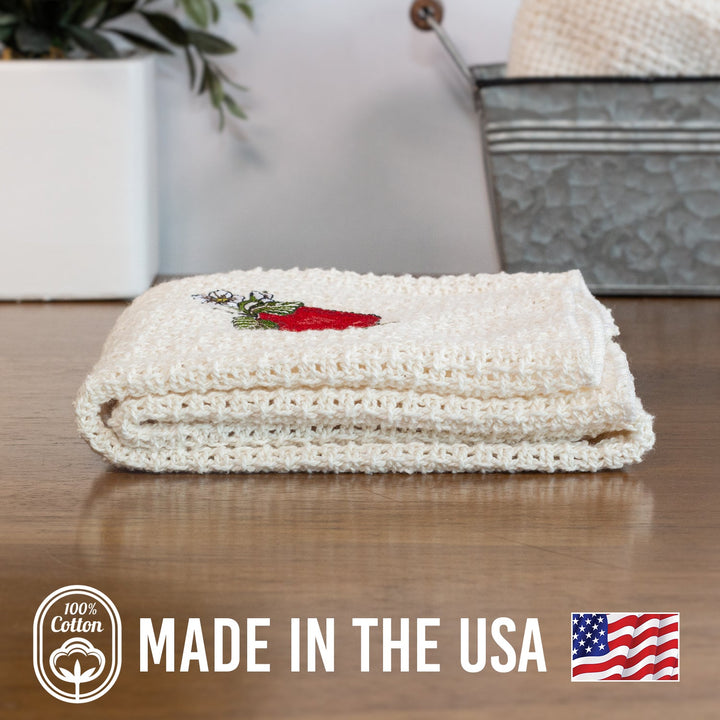 Off-white cotton kitchen towel folded with red cardinal embroidery