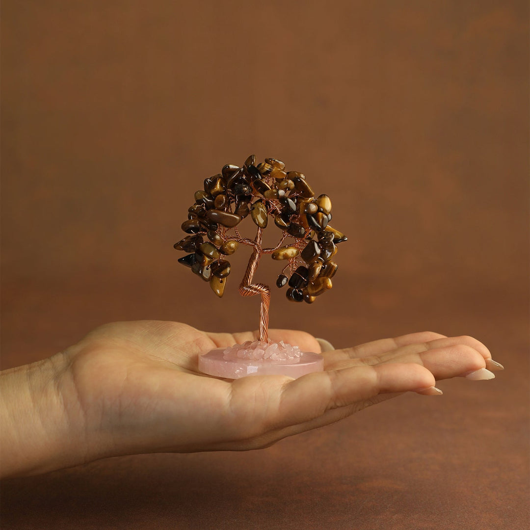 Golden-brown gemstone mini crystal tree on pink stone base, held in palm