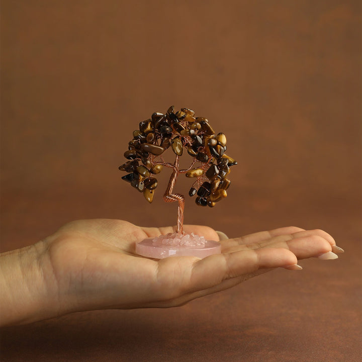 Golden-brown gemstone mini crystal tree on pink stone base, held in palm