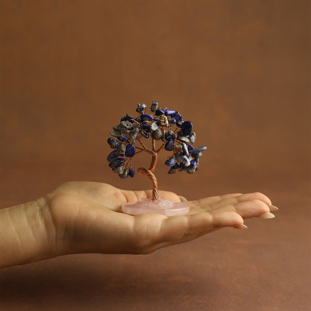 Blue gemstone mini crystal tree on pink stone base, held in open hand