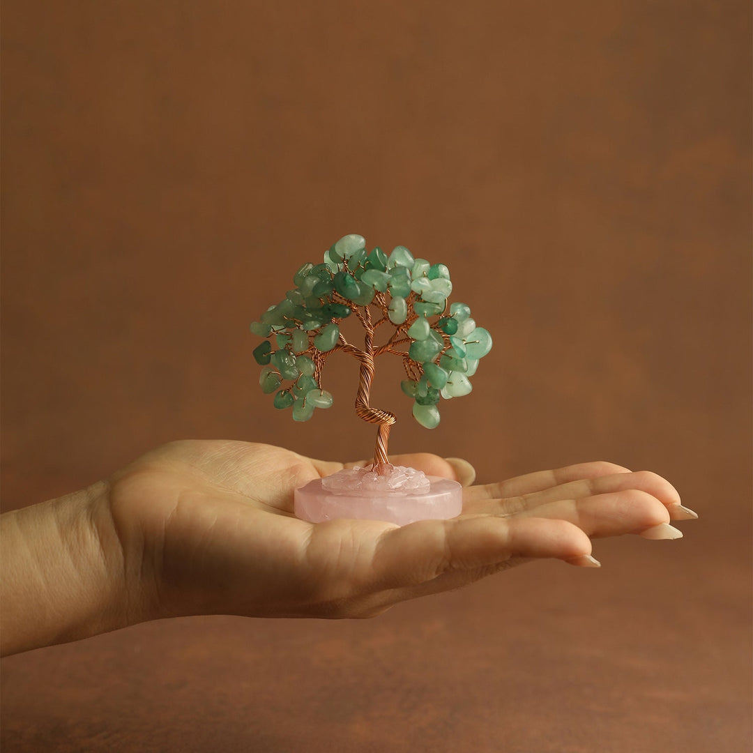 Green gemstone mini crystal tree on pink stone base, held in open palm