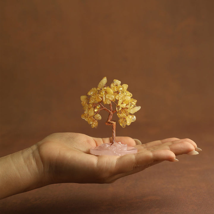 Yellow gemstone mini crystal tree on pink stone base, held in palm