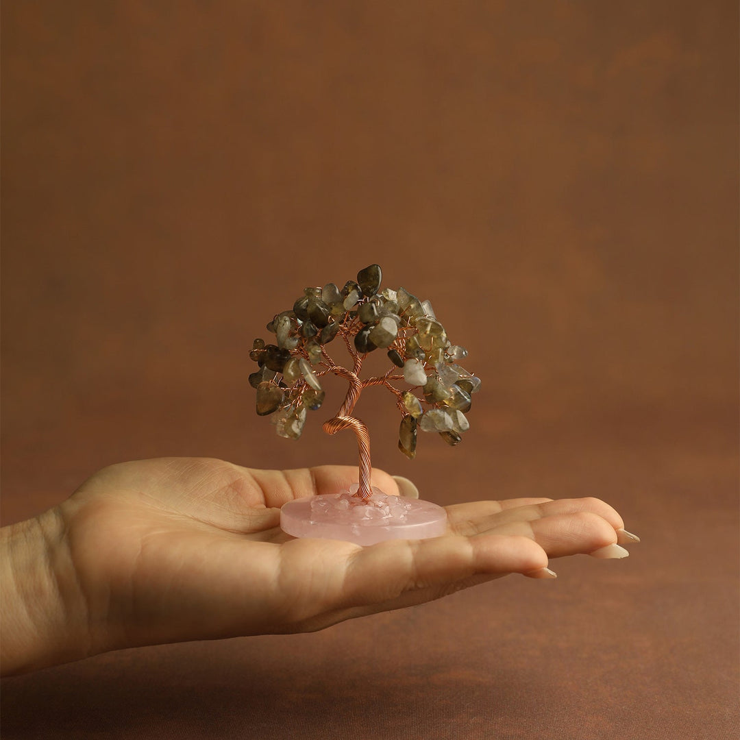 Clear gemstone mini crystal tree on pink stone base, held in open hand