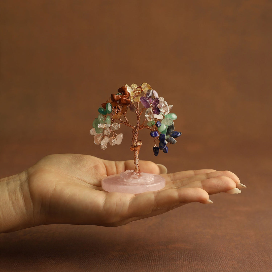 Mini crystal tree held in hands with multicolor gemstones on pink base