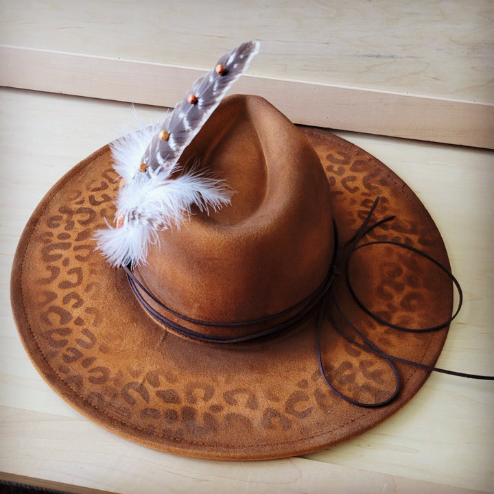 Leopard-print tan cowgirl hat with feather hatband and dark braided rope trim