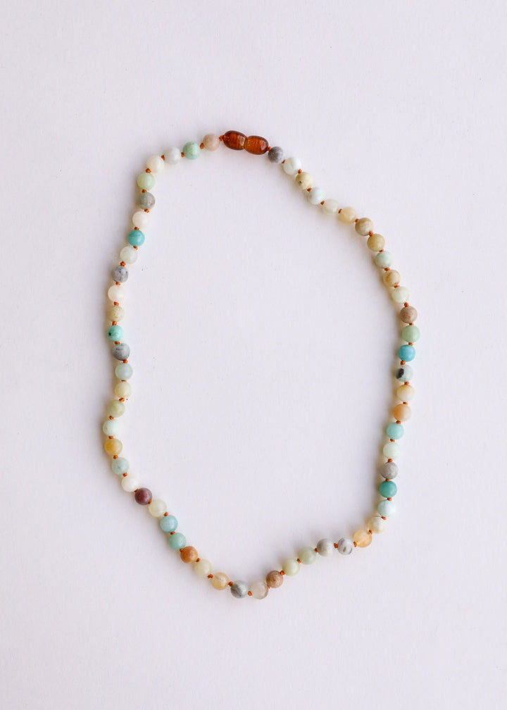 Beaded necklace laid flat: round white and aqua beads with brown spacer accents.
