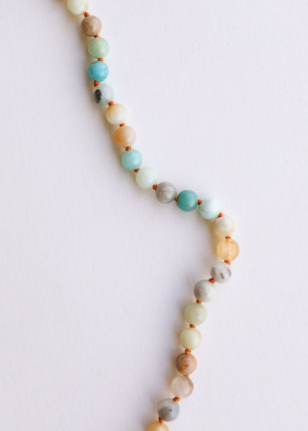 Necklace strand with round beads in white, aqua, and peach plus brown separator beads.