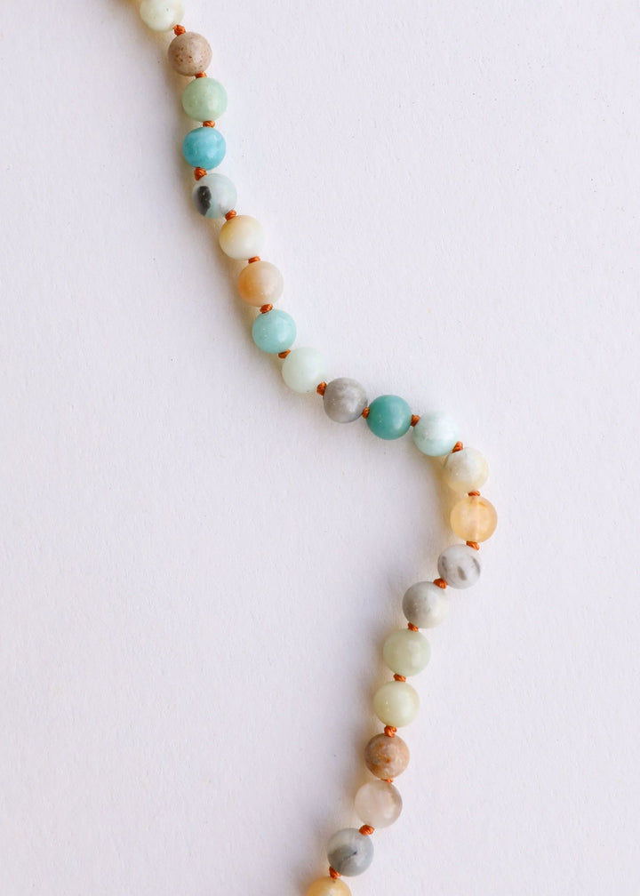 Necklace strand with round beads in white, aqua, and peach plus brown separator beads.