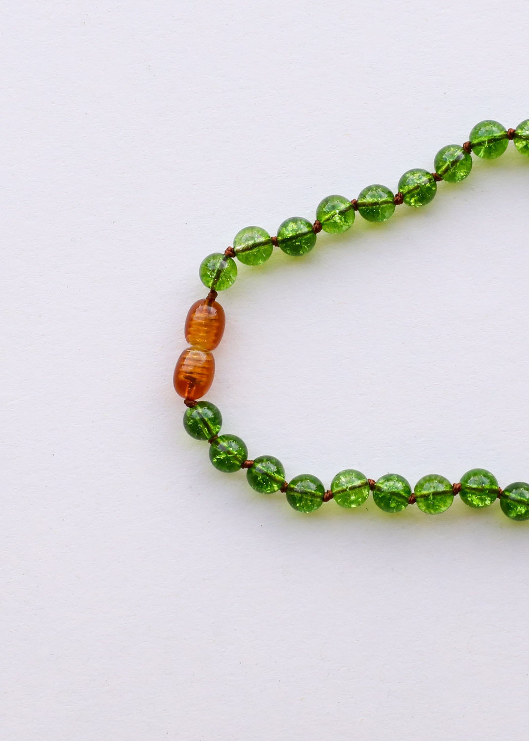 Close-up of peridot green beaded necklace with amber/golden bead detail