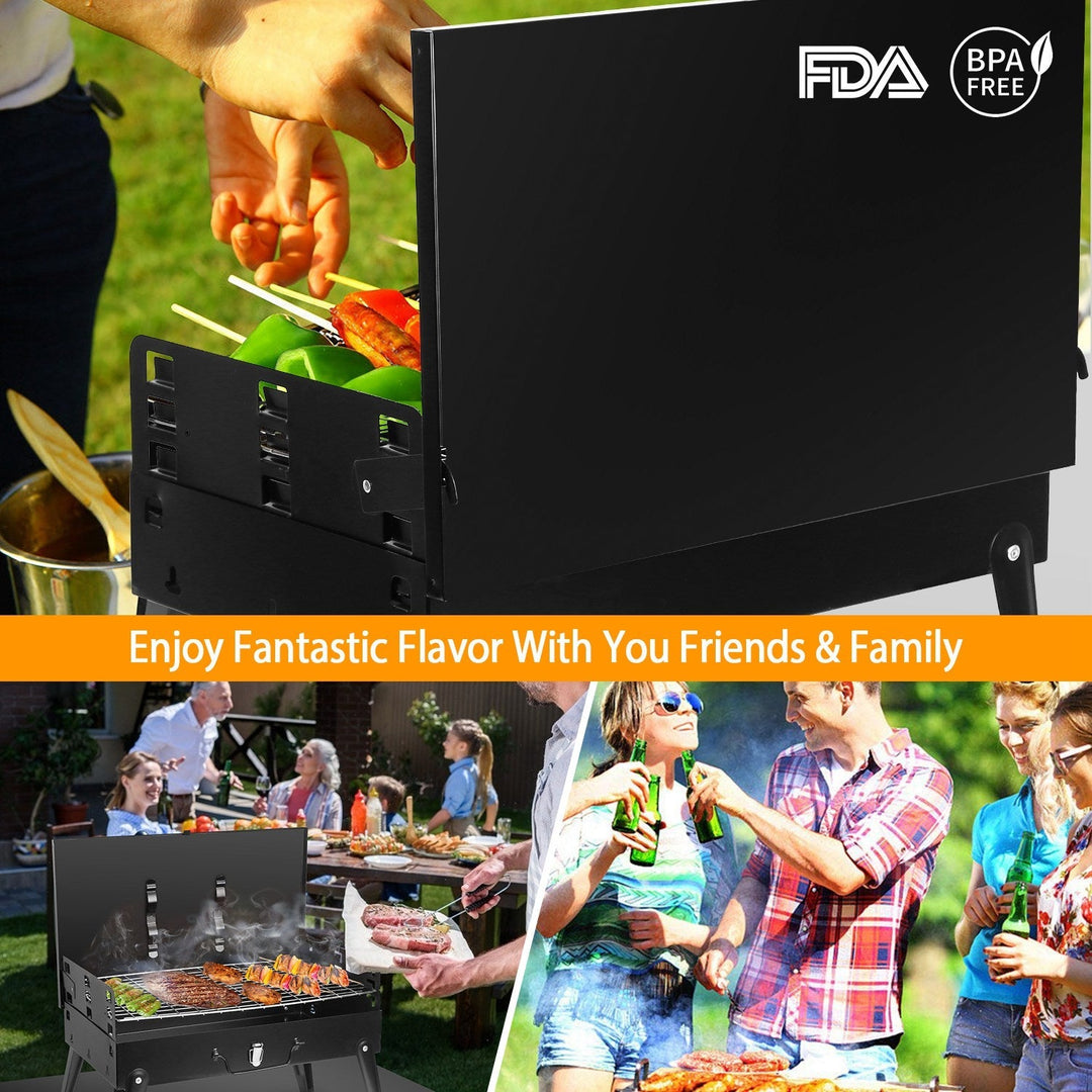 Black charcoal grill with open firebox and skewers, ready for outdoor cooking