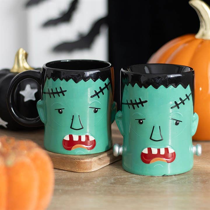 Halloween monster oil burners, two teal ceramic cups with black faces and stitched details.