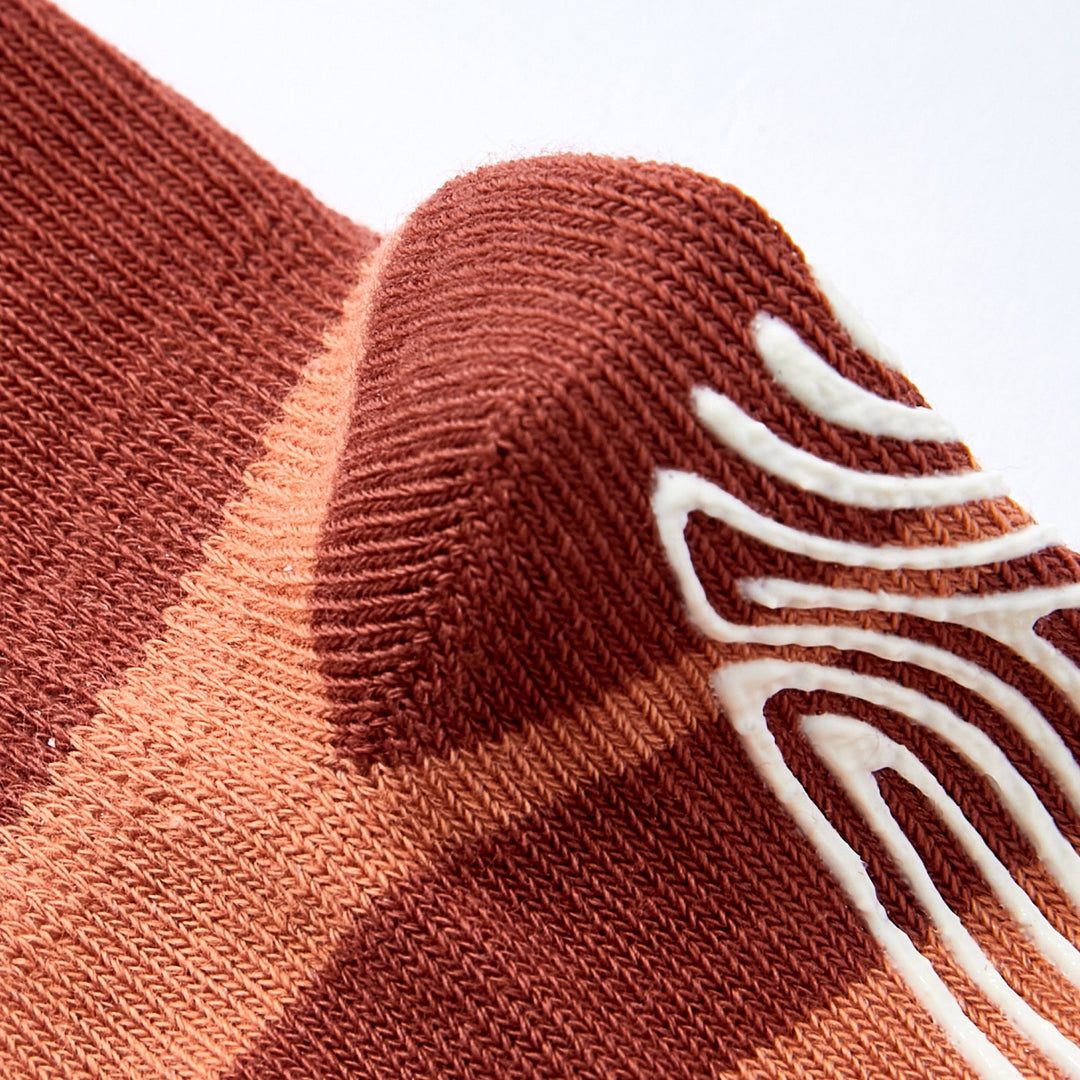Close-up of terracotta knit sock with white bear-face motif and ribbed cuff