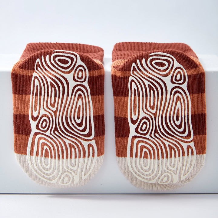 Pair of terracotta non-slip crew socks with bear pattern and white swirl lines