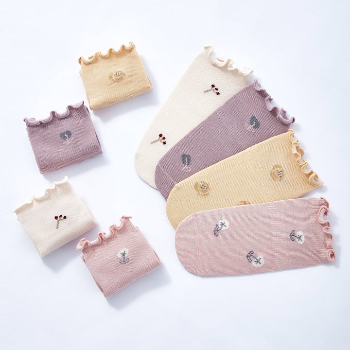 Baby non-slip socks flat lay in cream, lilac, beige, and pink with gripped toe areas