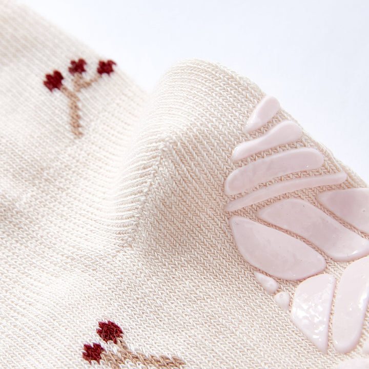 Close-up of cream baby non-slip sock knit with small embroidery and ruffled cuff