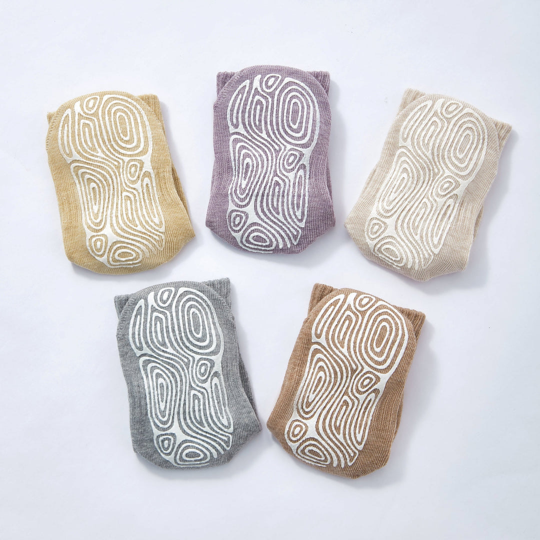 Baby non-slip socks set shown: cream, charcoal gray, lavender, tan, and mustard with swirls