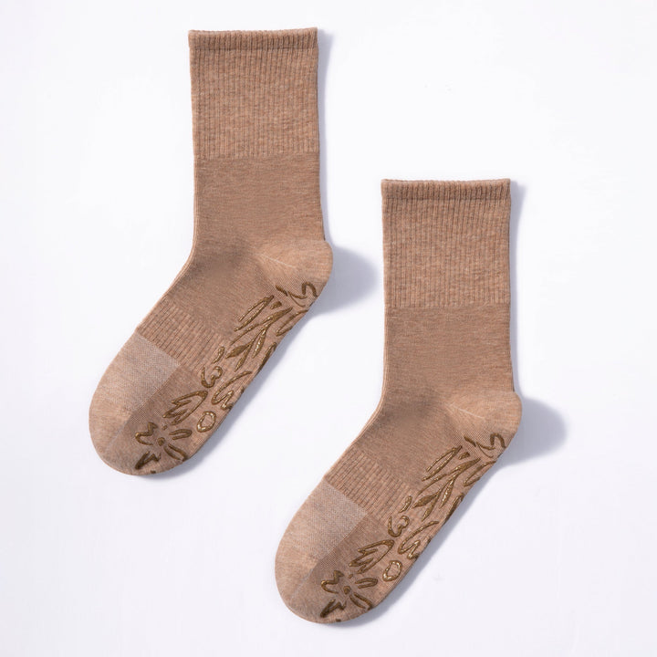 Two brown crew socks laid out, with printed grip dots on the soles