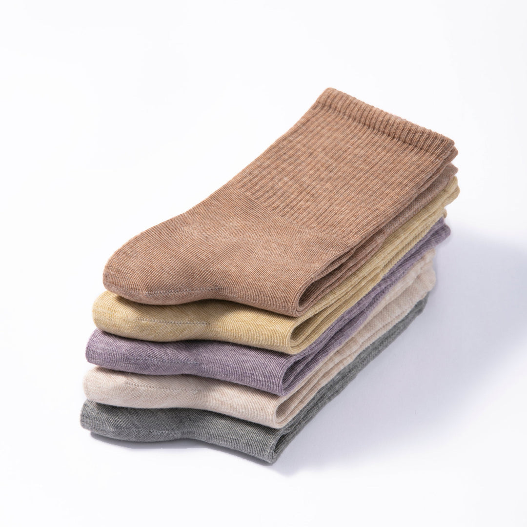 Stack of folded non-slip socks in tan, pale yellow, lavender and dark gray