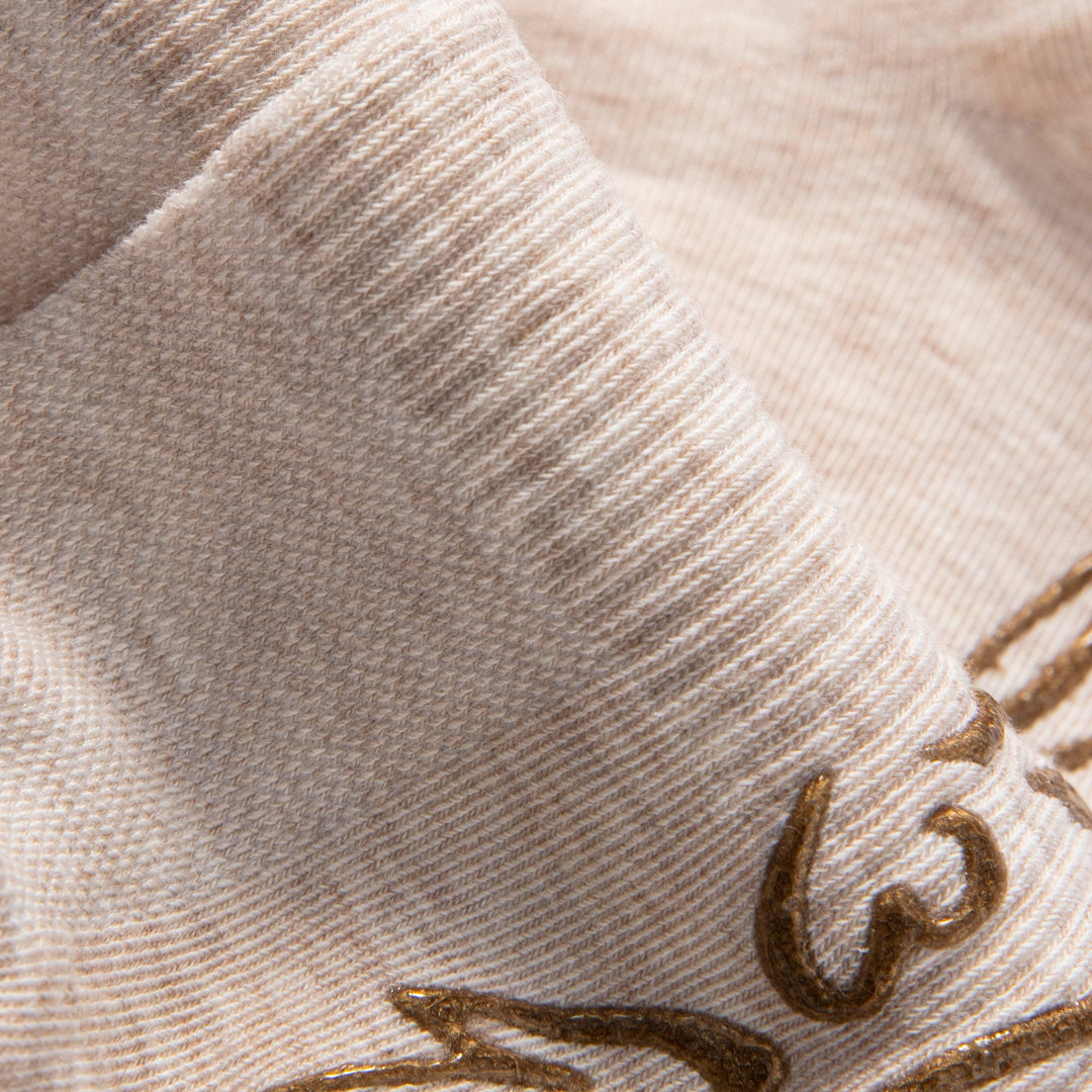 Close-up of beige sock knit with brown floral non-slip grip print