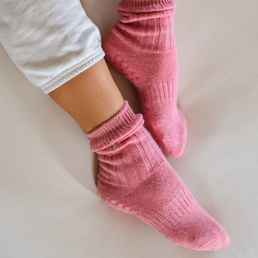 Coral ribbed crew socks with textured toe and heel grip, worn on a couch