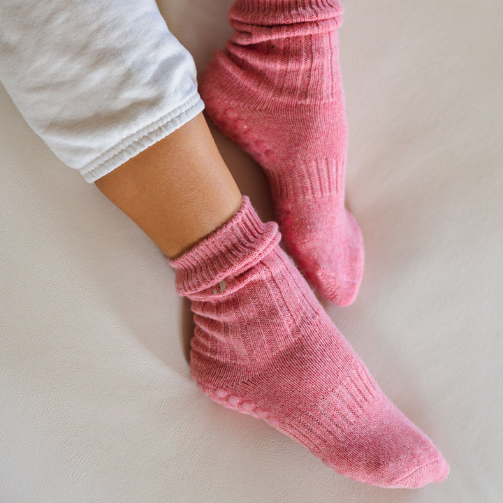 Coral ribbed crew socks with textured toe and heel grip, worn on a couch