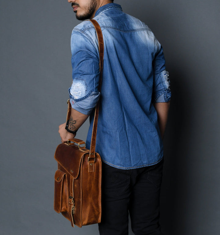 Brown leather crossbody bag worn at side, with top handle and front flap